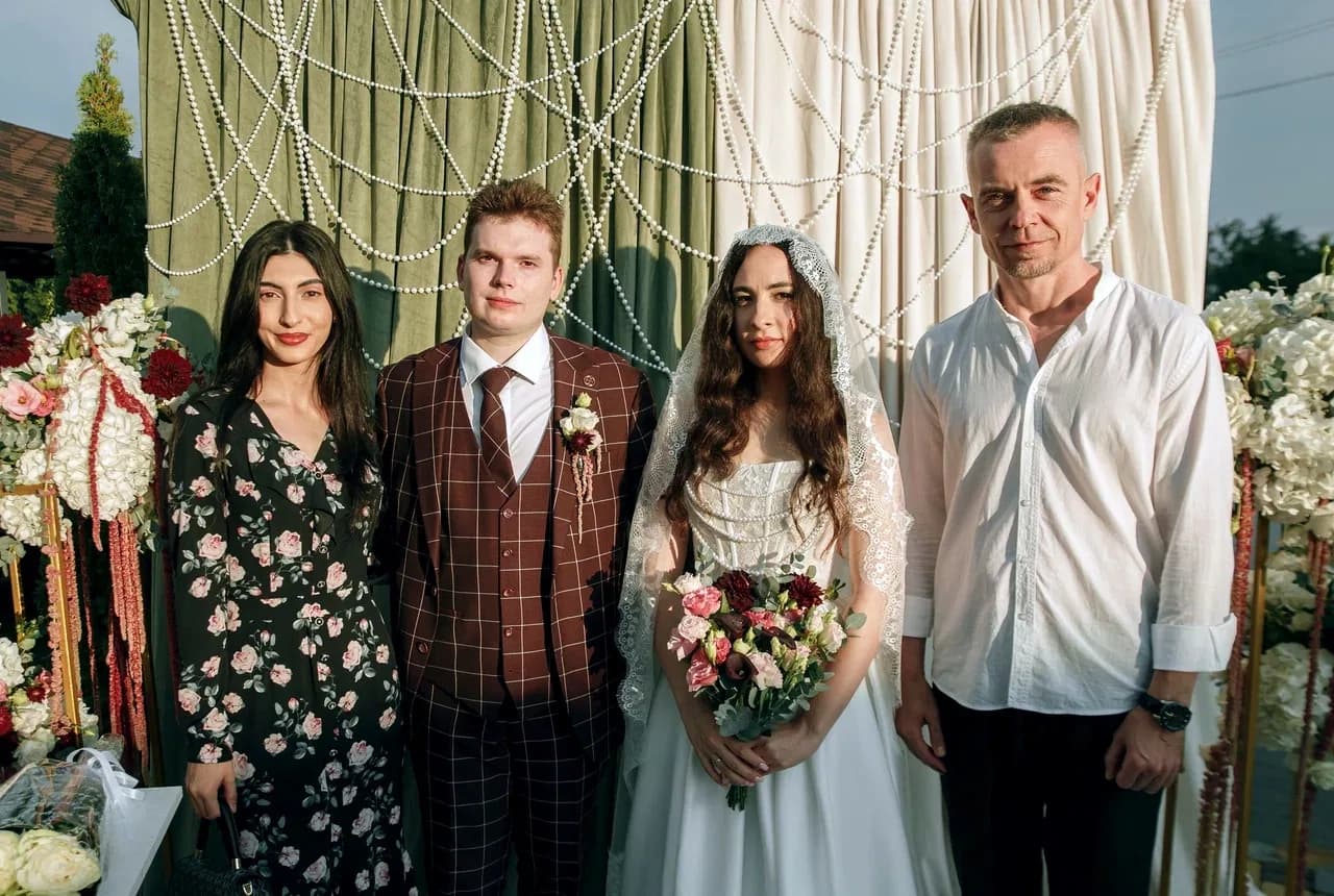 Невеста с женихом и гостями у свадебной фотозоны